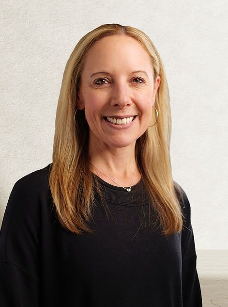 A smiling woman with long blonde hair, wearing a dark top, against a plain white background.