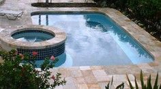 Small pool with attached round hot tub surrounded by tile.