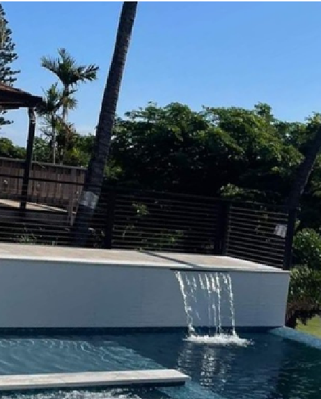 A pool with a waterfall and chairs