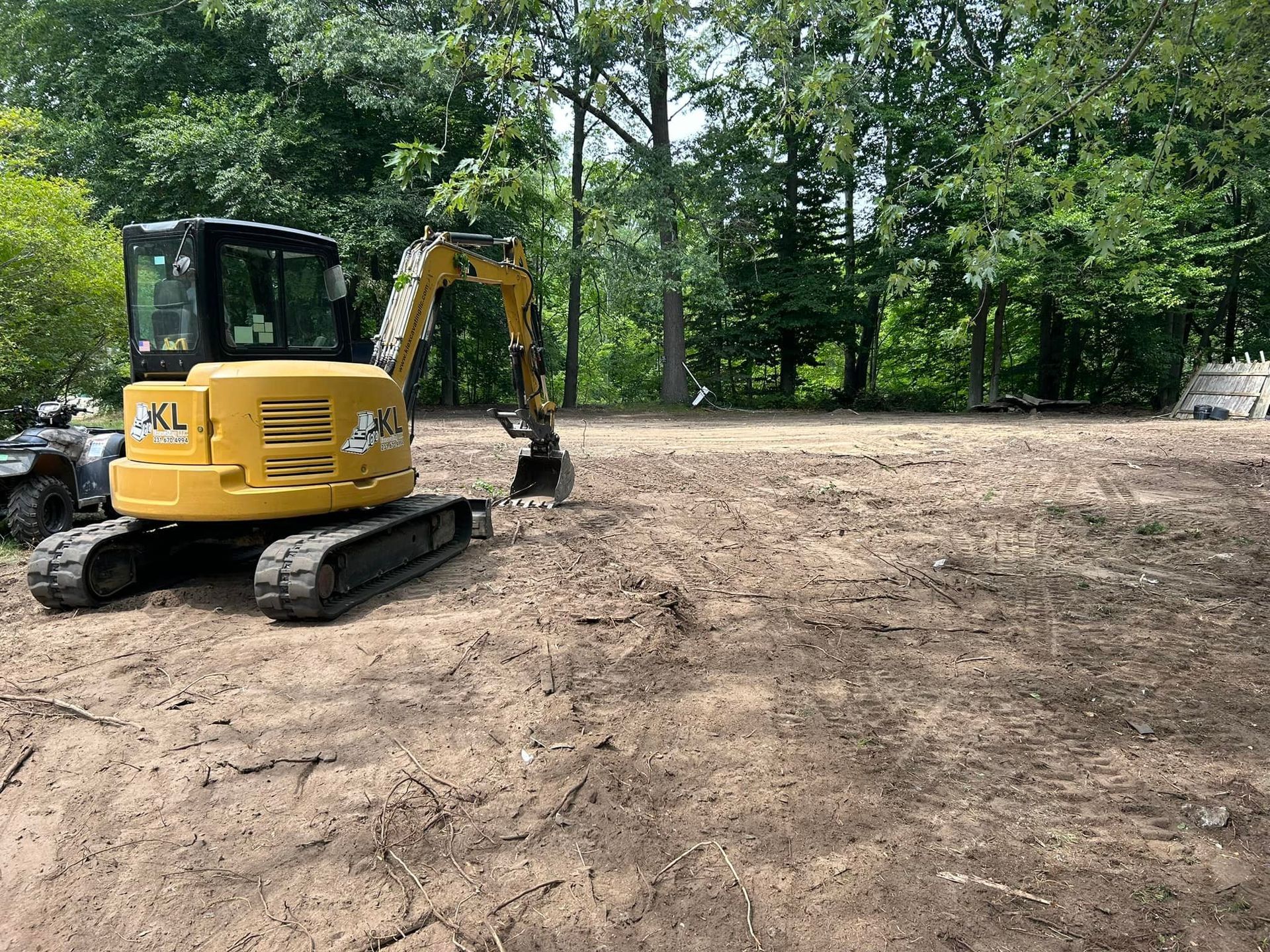 A yellow excavator is sitting in the middle of a dirt field.