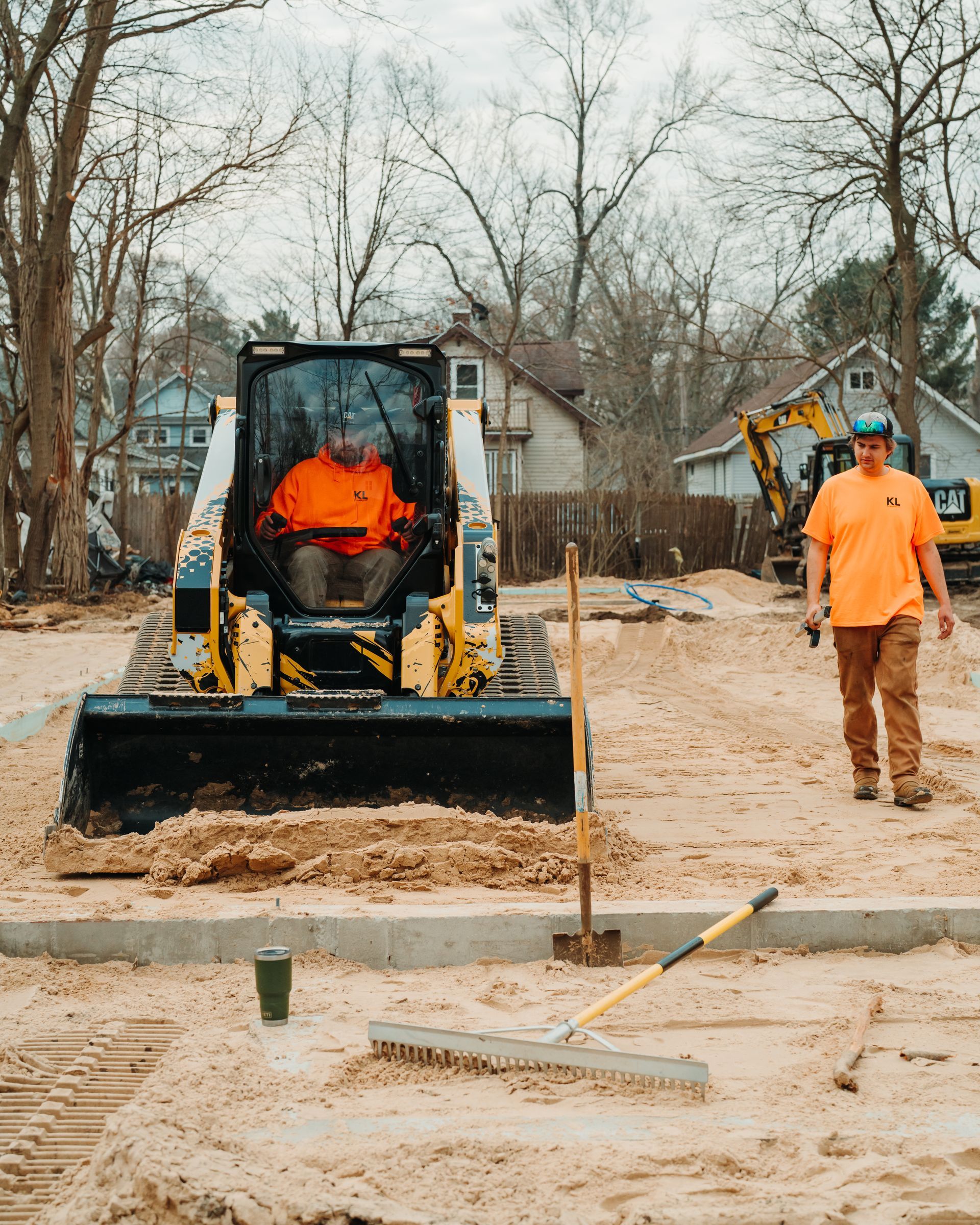 A yellow excavator is sitting in the middle of a dirt field.