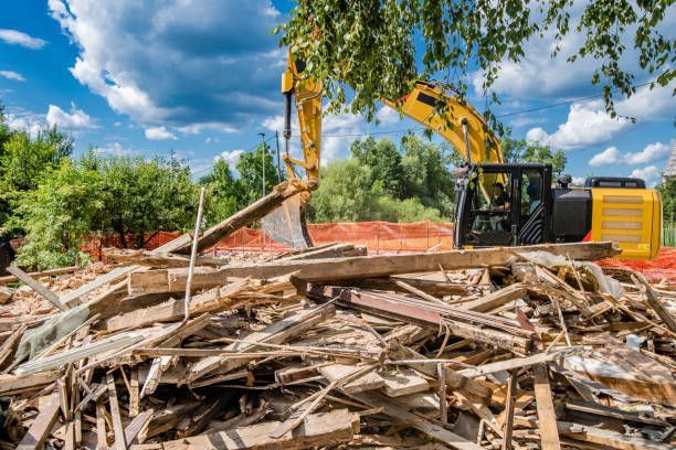 A yellow excavator is working on a pile of wood.