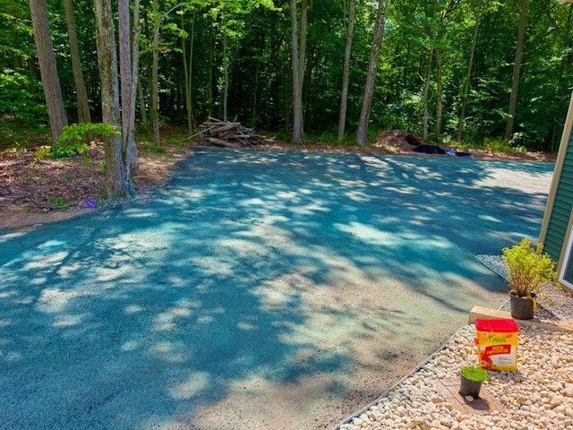 A driveway surrounded by trees and gravel in the middle of a forest.