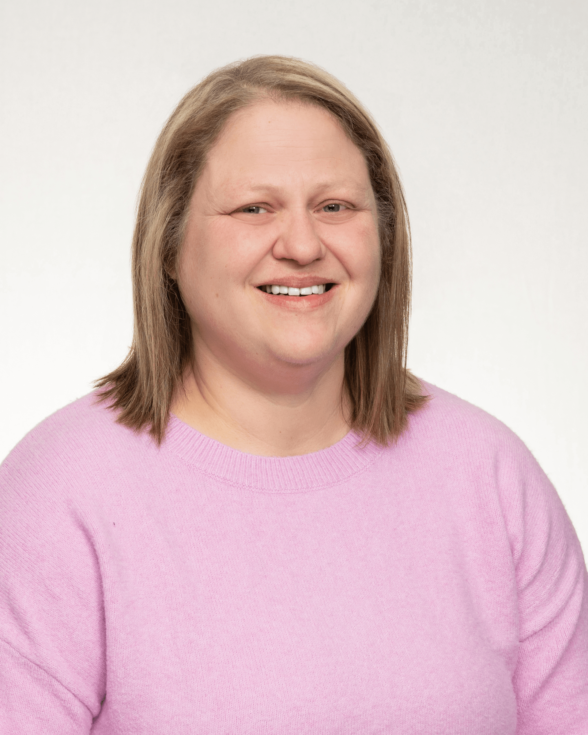 a woman in a pink sweater is smiling for the camera .