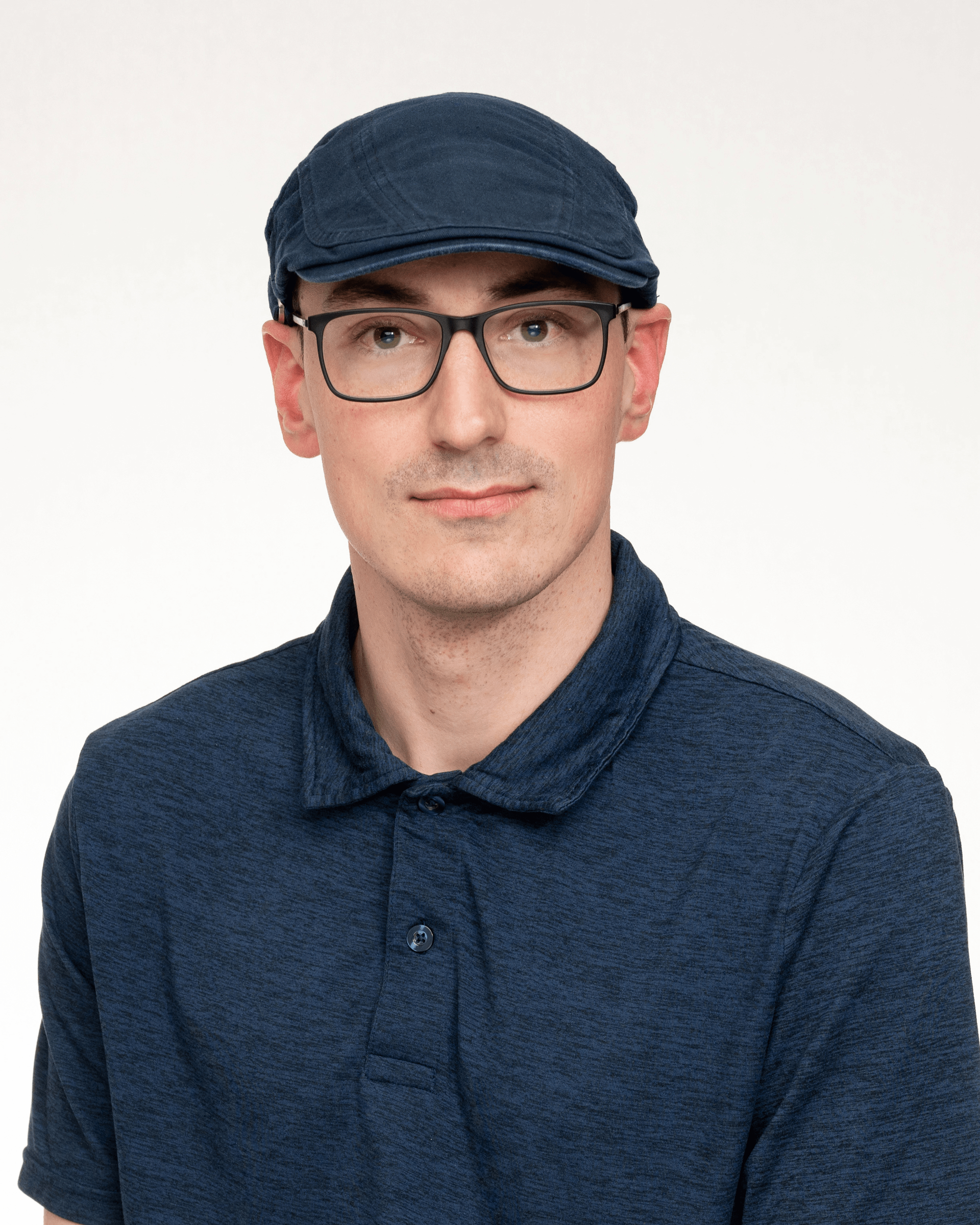 a man wearing glasses and a hat is standing in front of a white background .
