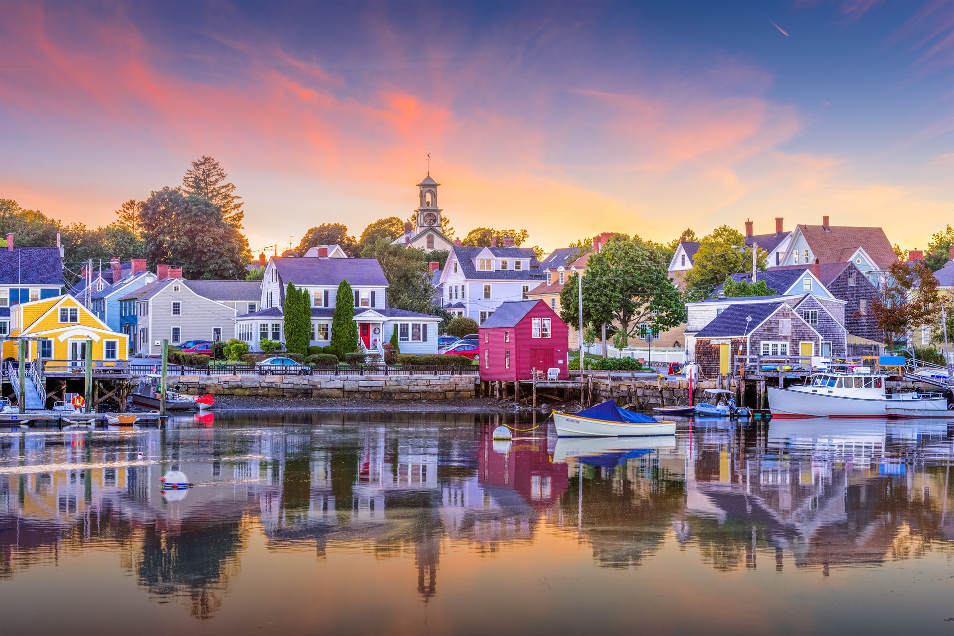 a small town on the shore of a body of water at sunset .