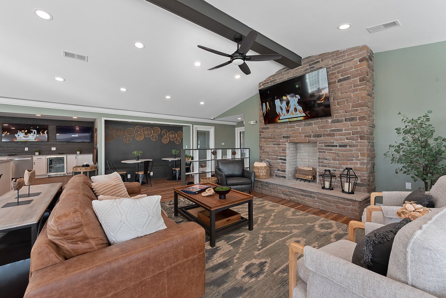 Lounge area with fireplace, TV, and seating. Brick fireplace, leather sofa, and coffee table are focal points.