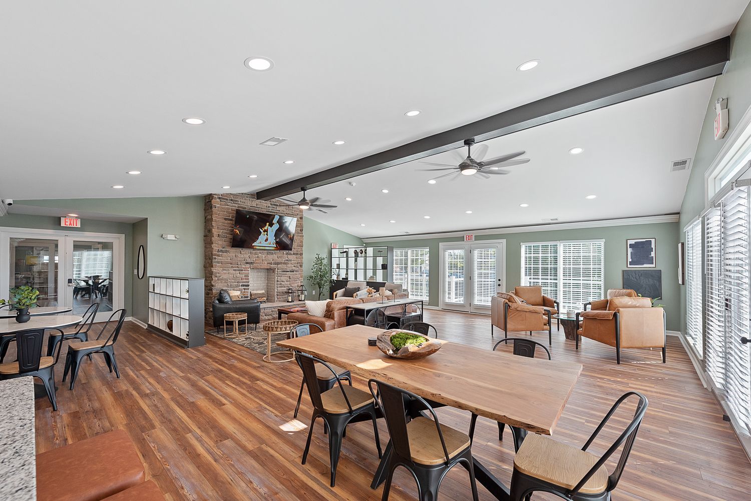 Spacious lounge area with wood floors, dining table, fireplace, and seating. Bright, airy setting with windows.