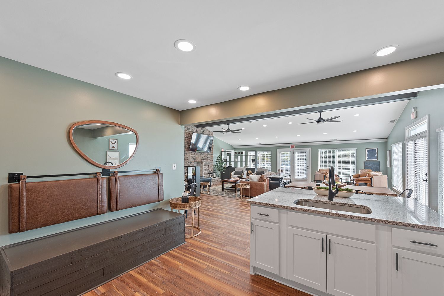 Open-concept kitchen with white cabinets, island, and seating area with a bench and mirror.