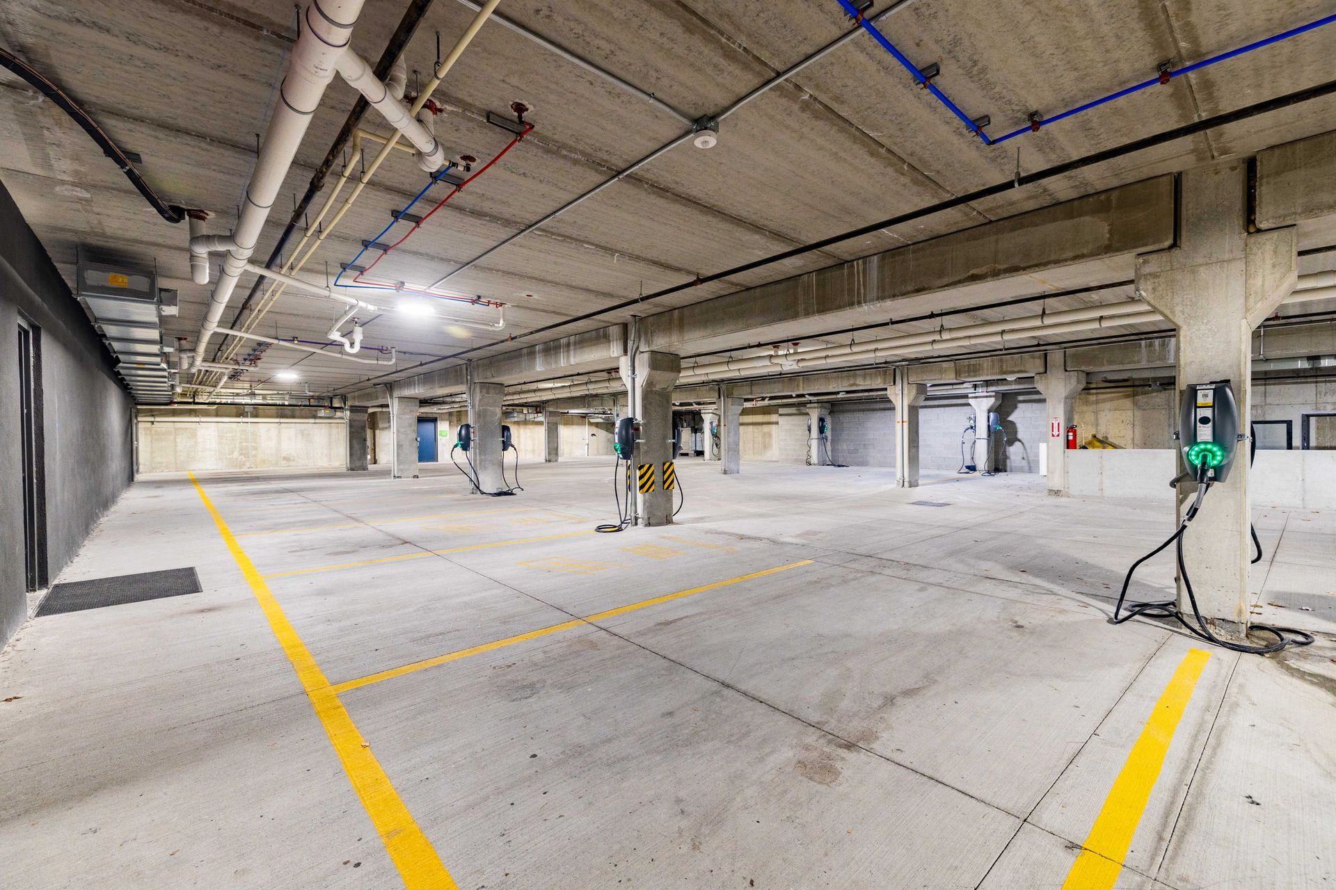 Empty underground parking garage with yellow lane markings and exposed ceiling pipes