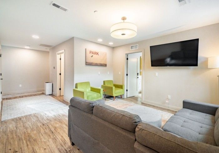 Living room with gray sofa, green chairs, and large TV.