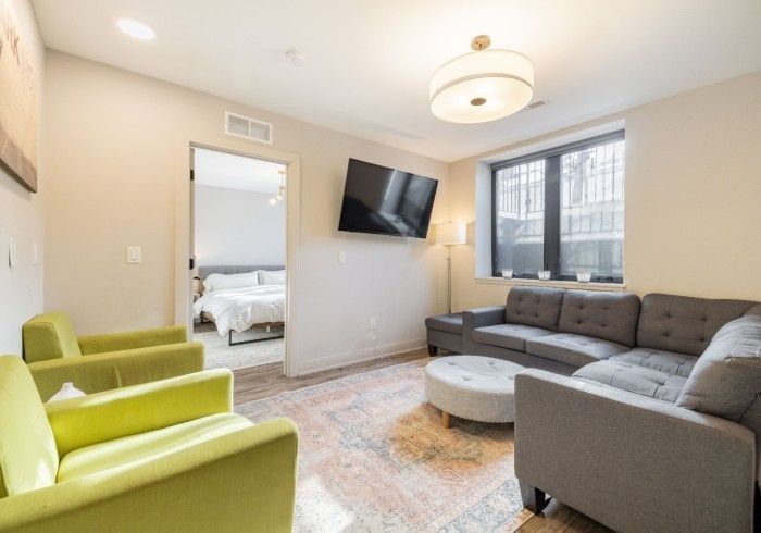 Living room with gray sectional, lime green chairs, and open doorway to bedroom.