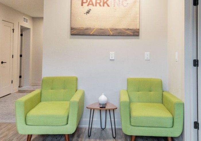 Two lime green armchairs flank a small table; artwork hangs above.