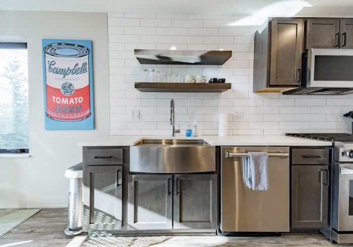 Modern kitchen with gray cabinets, stainless steel sink, and Campbell's soup can art.