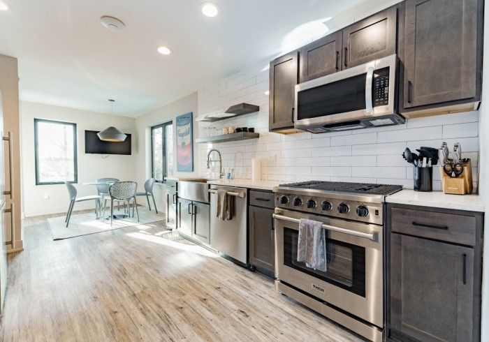 Modern kitchen with gray cabinets, stainless steel appliances, and a dining area.