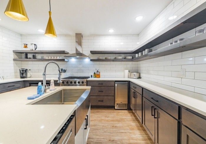 Modern kitchen with gray cabinets, white countertops, and wooden open shelves.