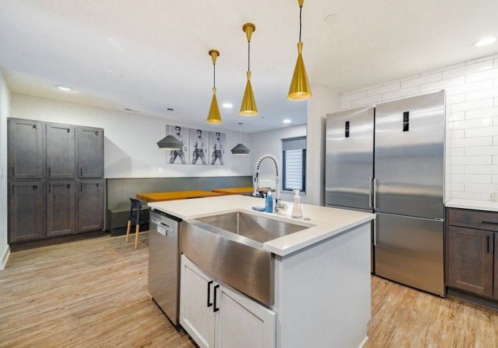 Modern kitchen with stainless steel appliances, island sink, and gold pendant lights.