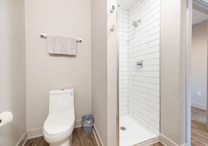 Bathroom with white toilet, shower, and towel rack on a neutral wall.