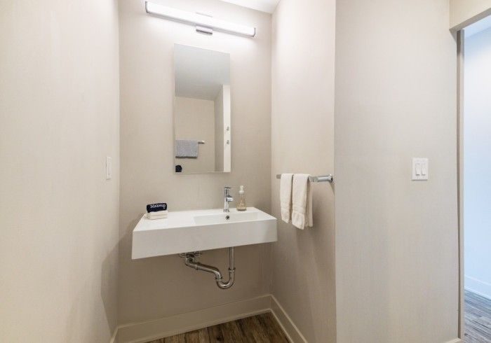 Small bathroom with a floating white sink, mirror, and towel rack.