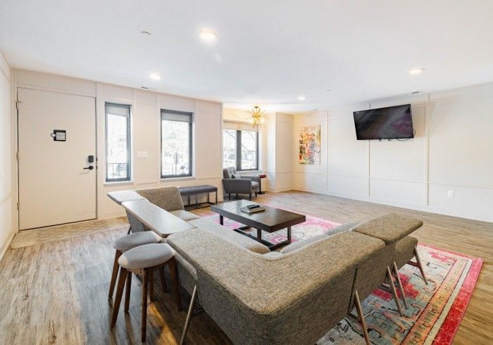 Spacious modern living room with gray sectional, TV, windows, and neutral walls.