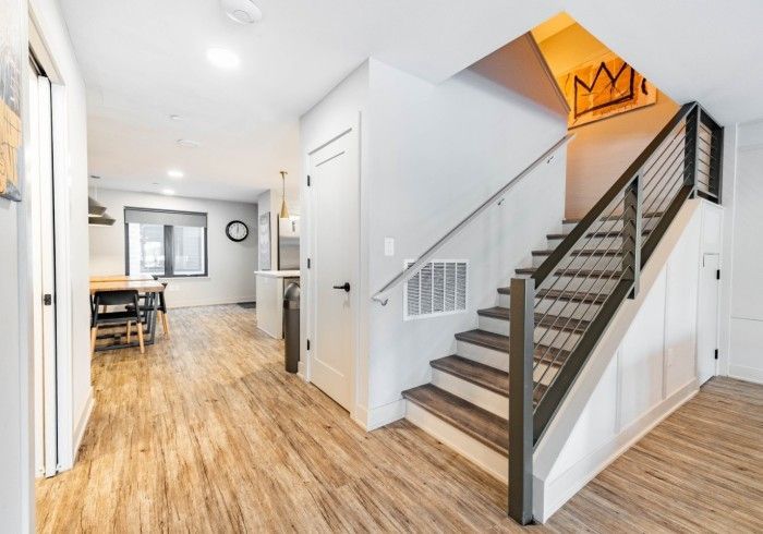 Interior of a home with a staircase, wooden floors, and a dining area visible in the background.