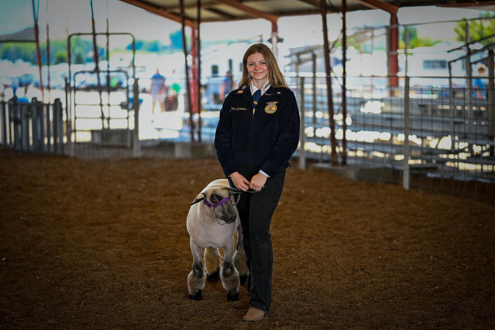 A woman in white pants holding a cow at fair
