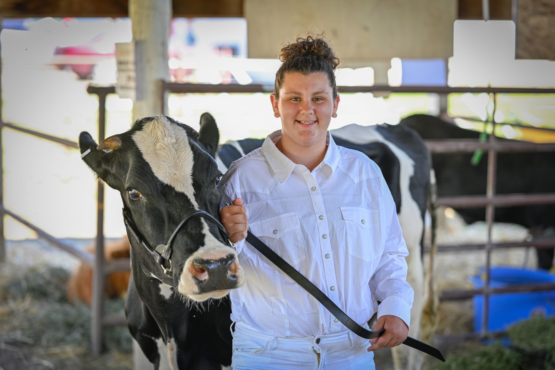 A young woman is standing next to a black and white cow.