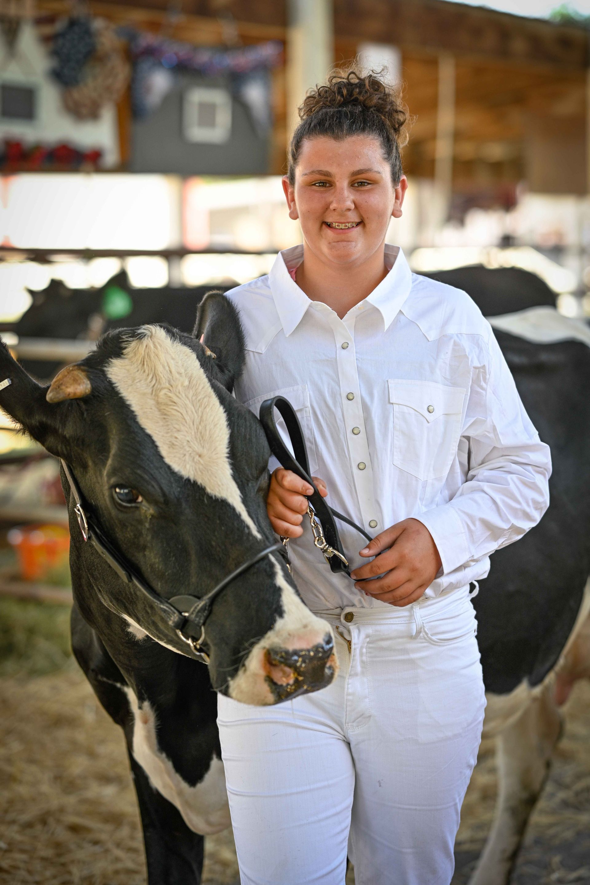 A young woman is standing next to a black and white cow.