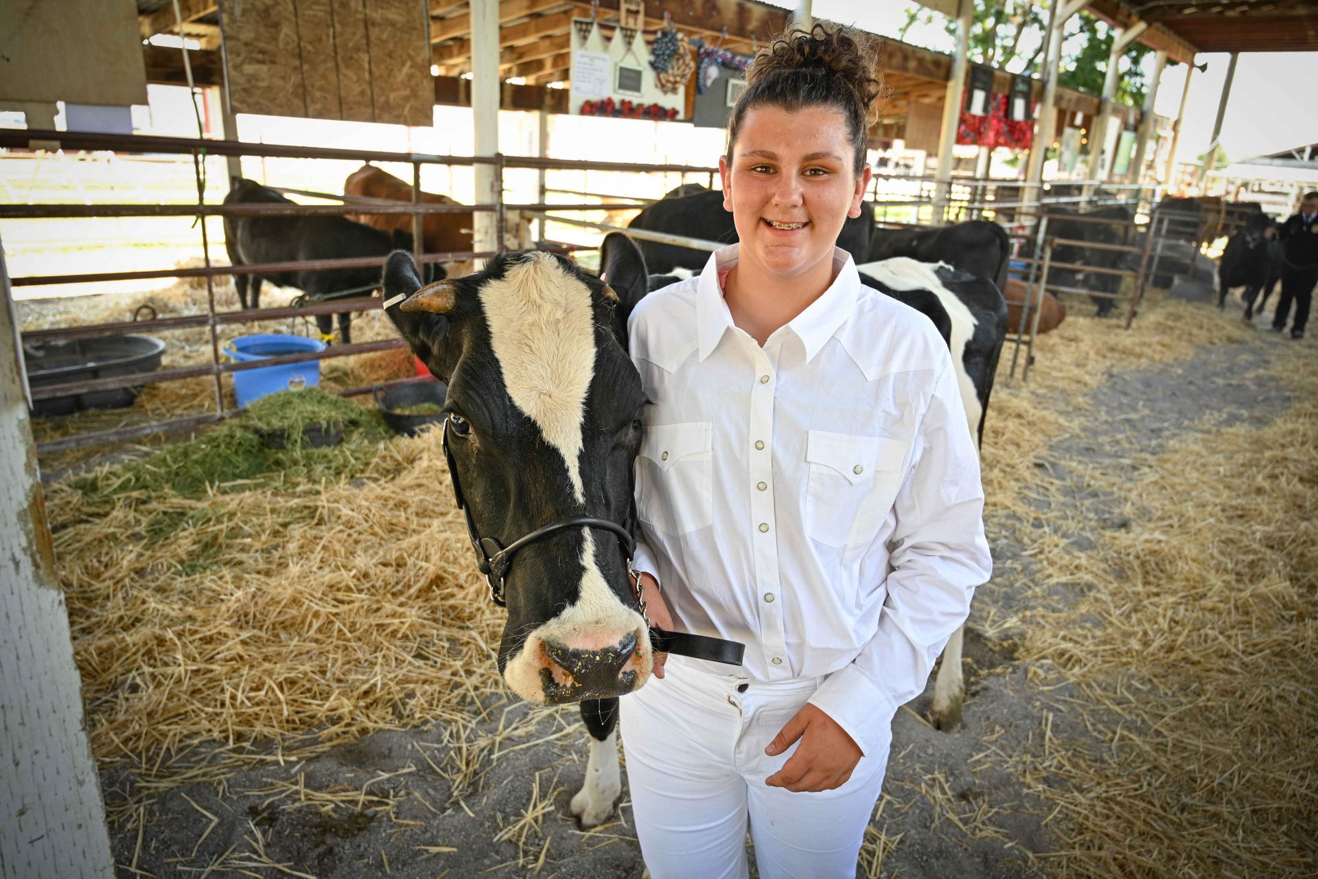 A woman in a white shirt is standing next to a black and white cow.