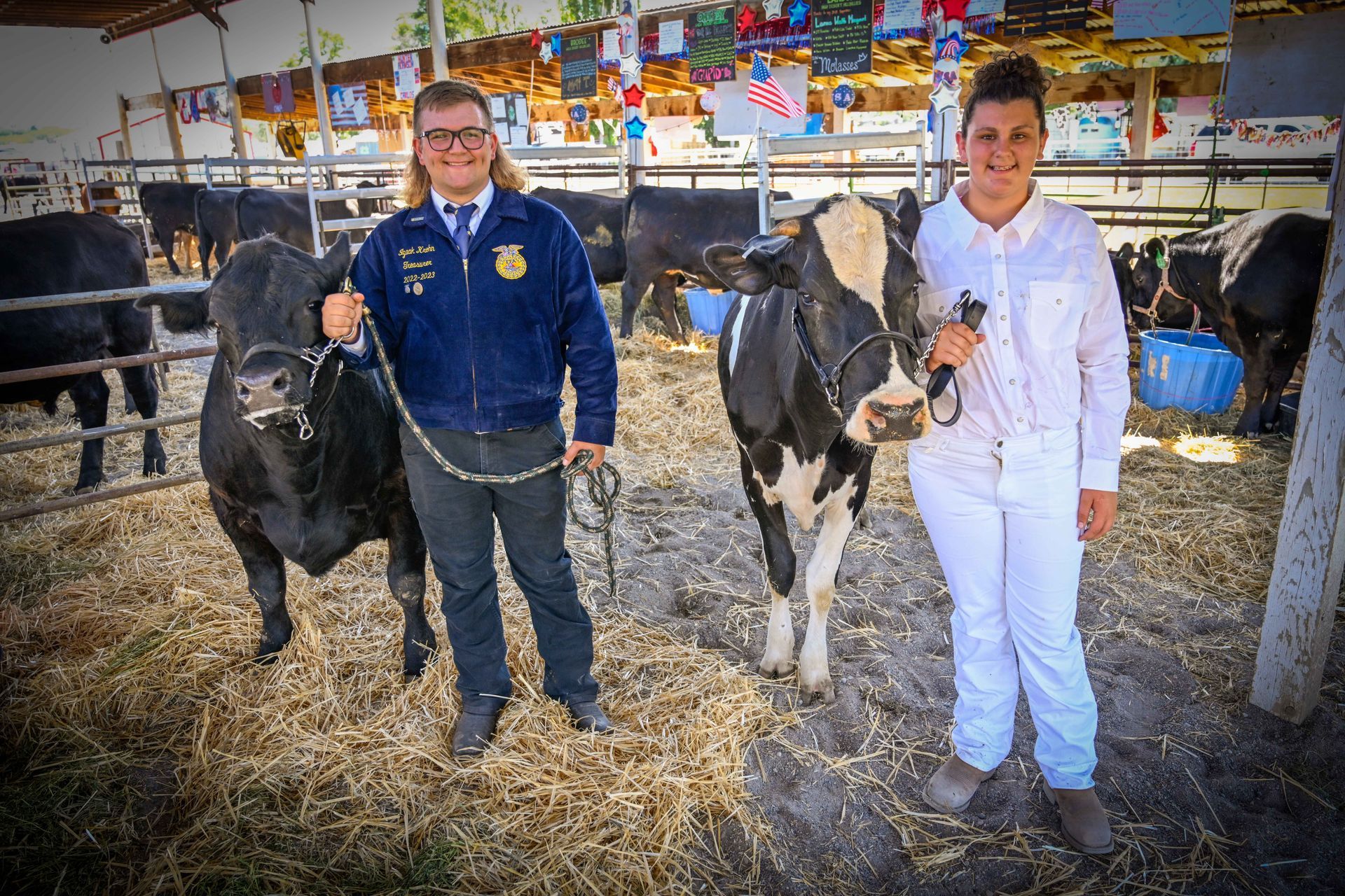 A man and a woman are standing next to a cow in a pen.