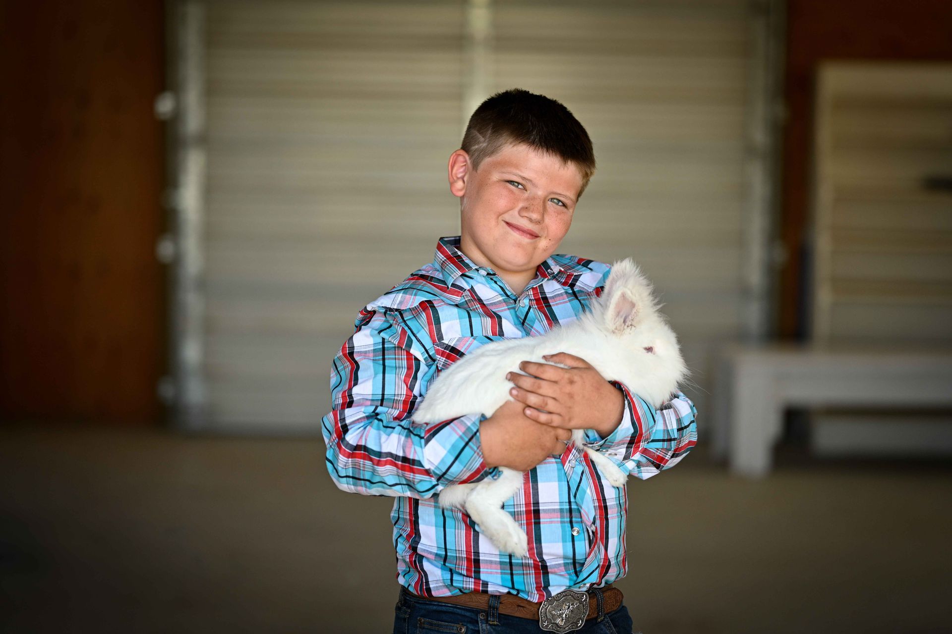 A young boy is holding a white rabbit in his arms.