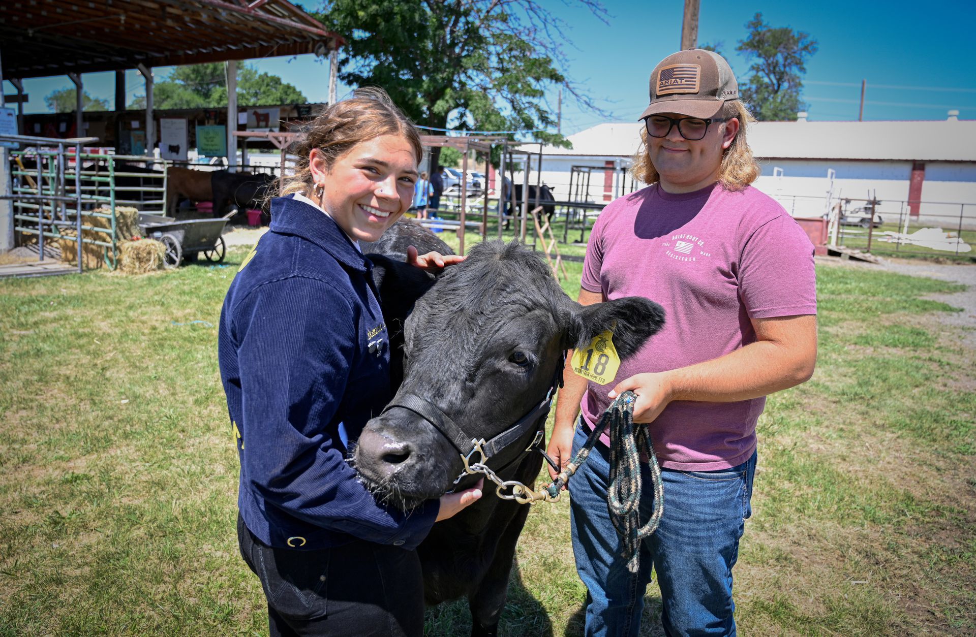 A man and a woman are holding a cow in a field.