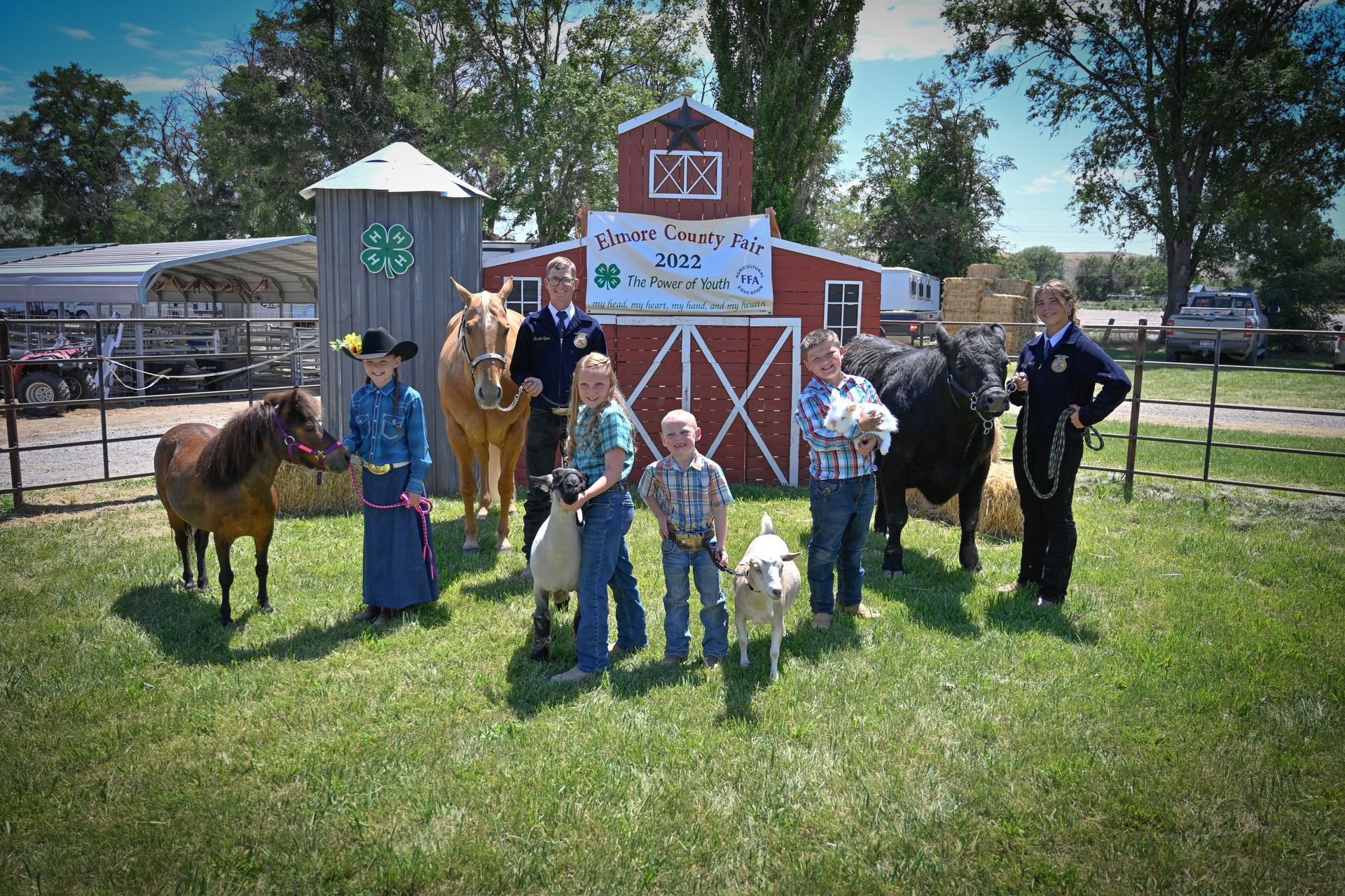 A group of people standing in front of a barn with animals.