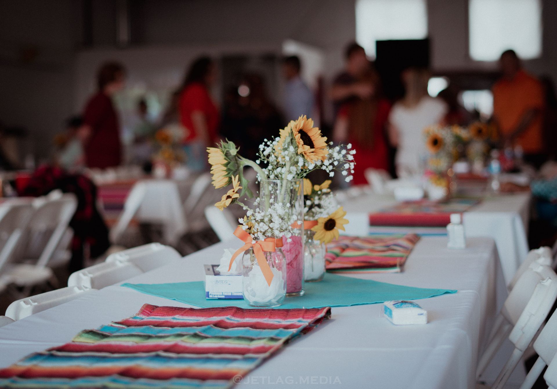 A table set up for a party with flowers in vases on it.