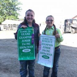 Two young women are standing next to each other holding signs.