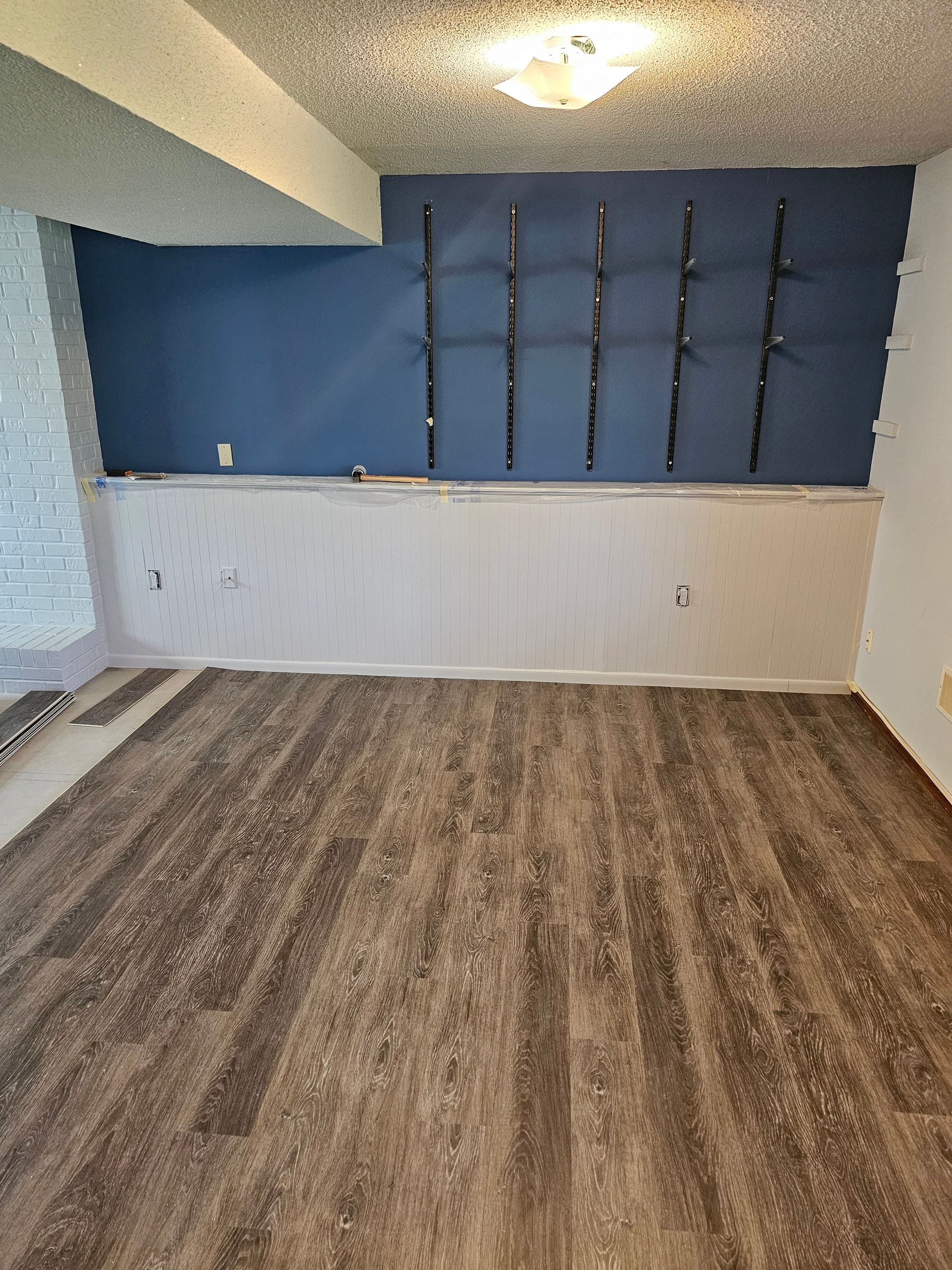 An empty room with a wooden floor and a blue wall.