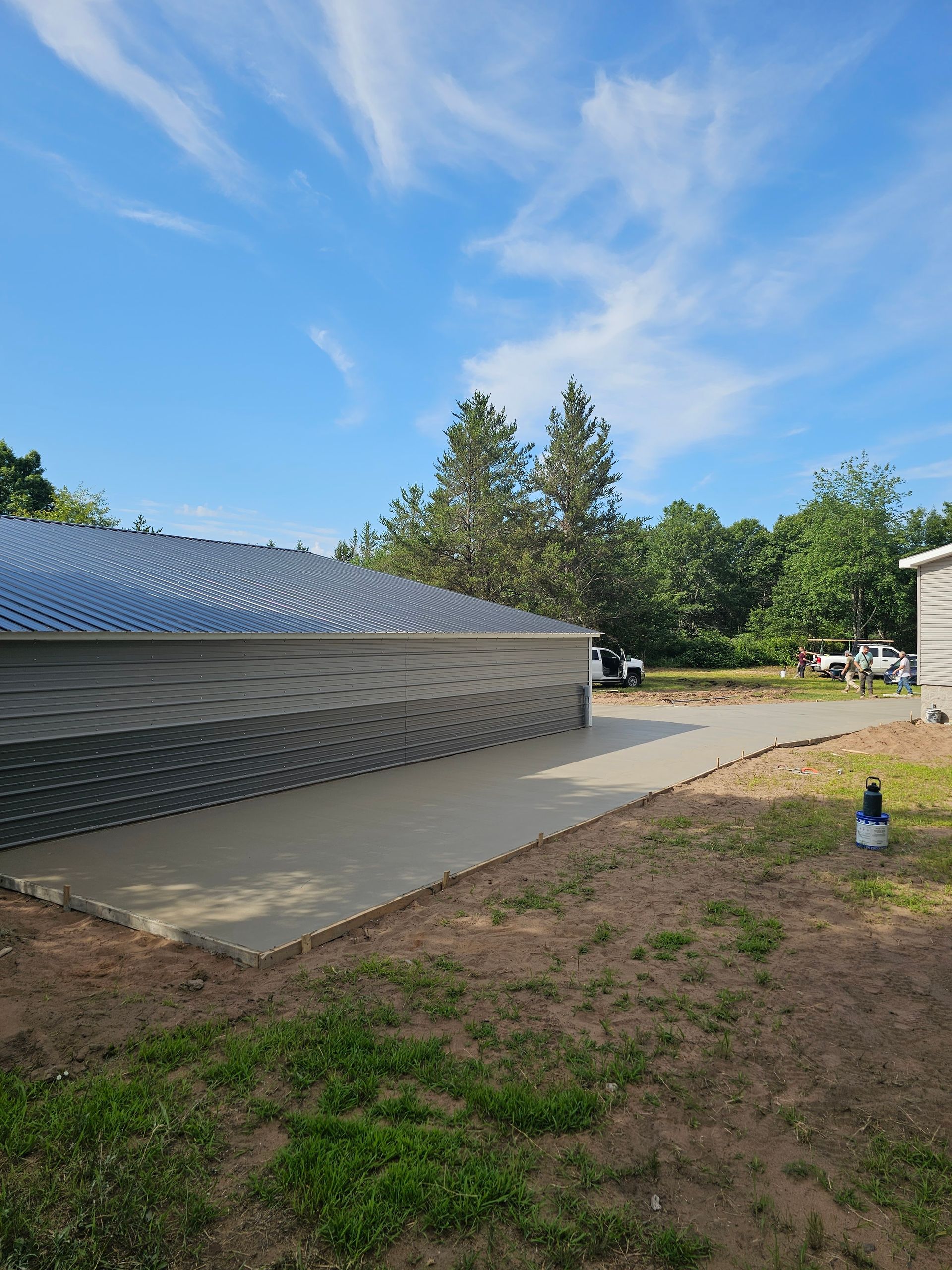 A concrete driveway leading to a house with a blue sky in the background.