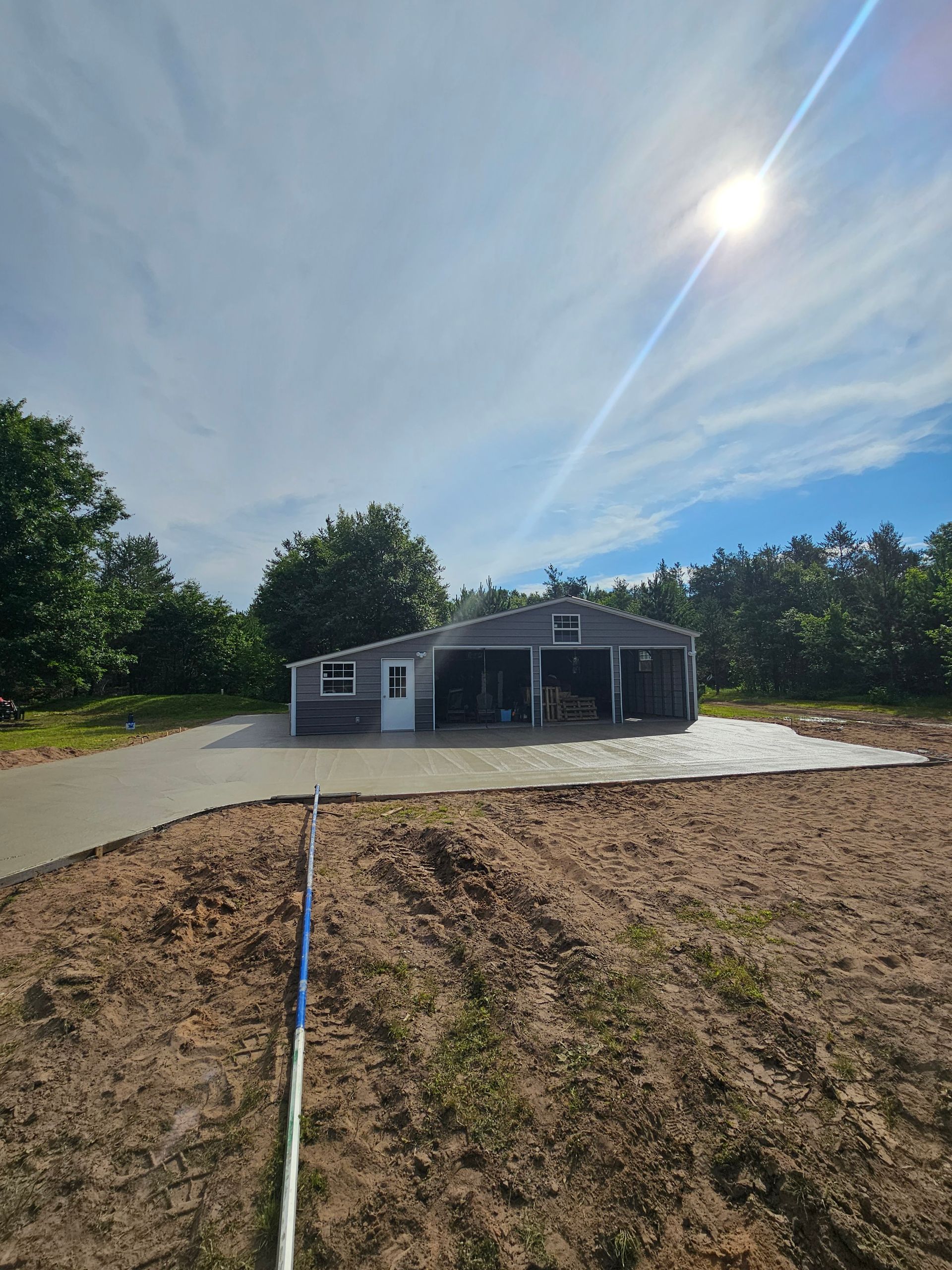 A house with a garage and a driveway is sitting on top of a dirt field.