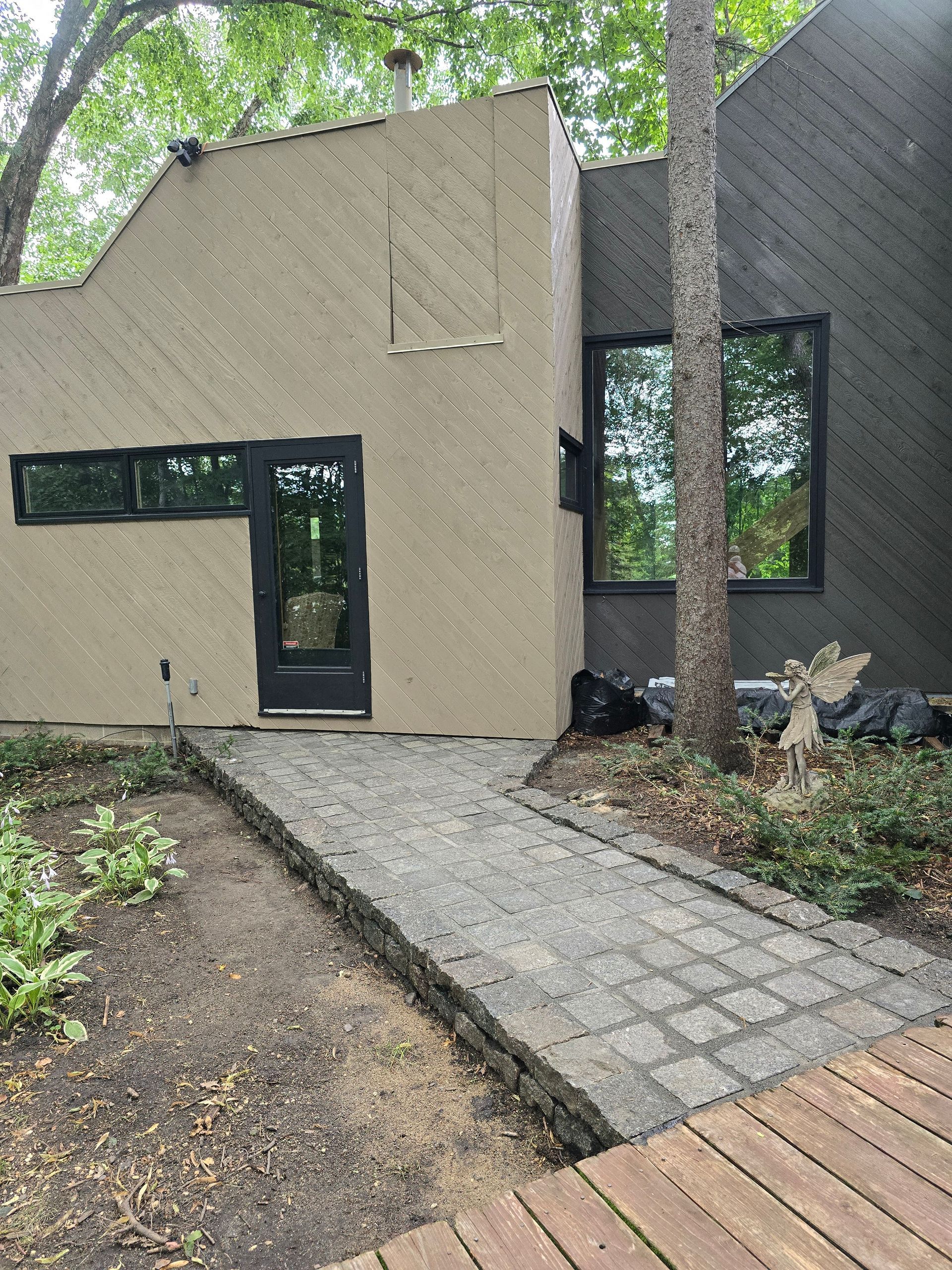 A house with a walkway leading to it and trees in front of it.