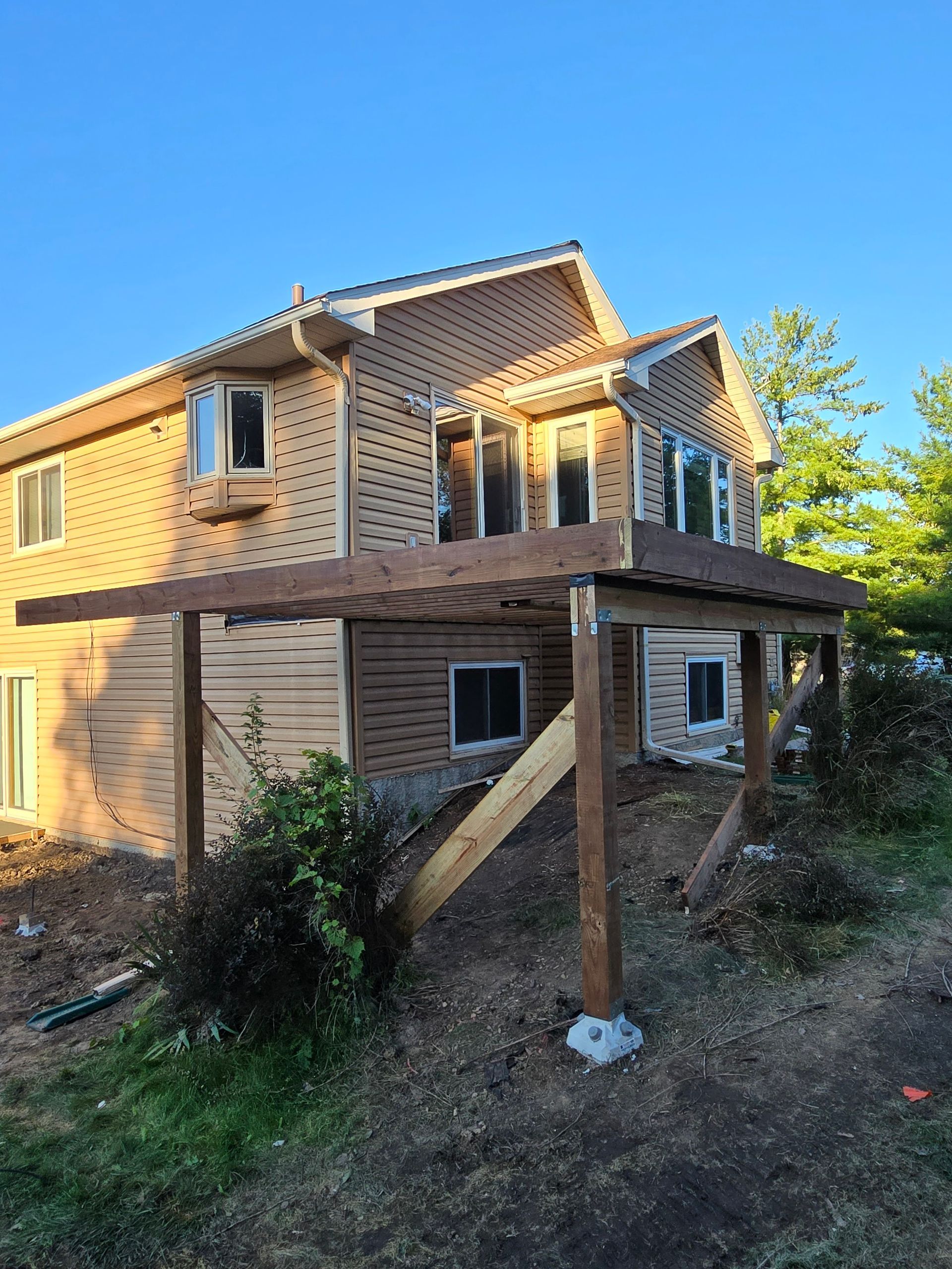 A house under construction with a wooden pergola in front of it.
