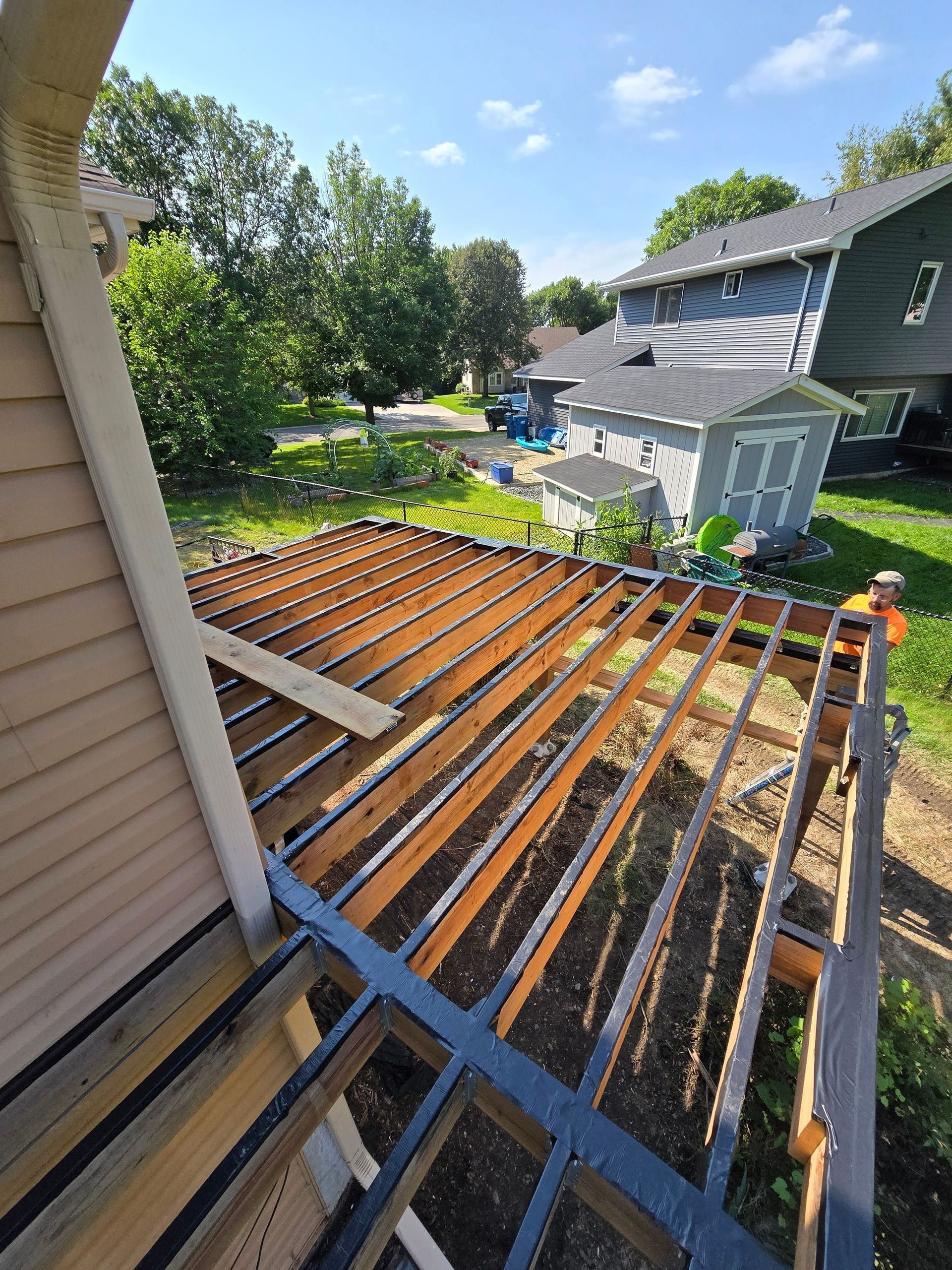 A wooden deck is being built on the side of a house.