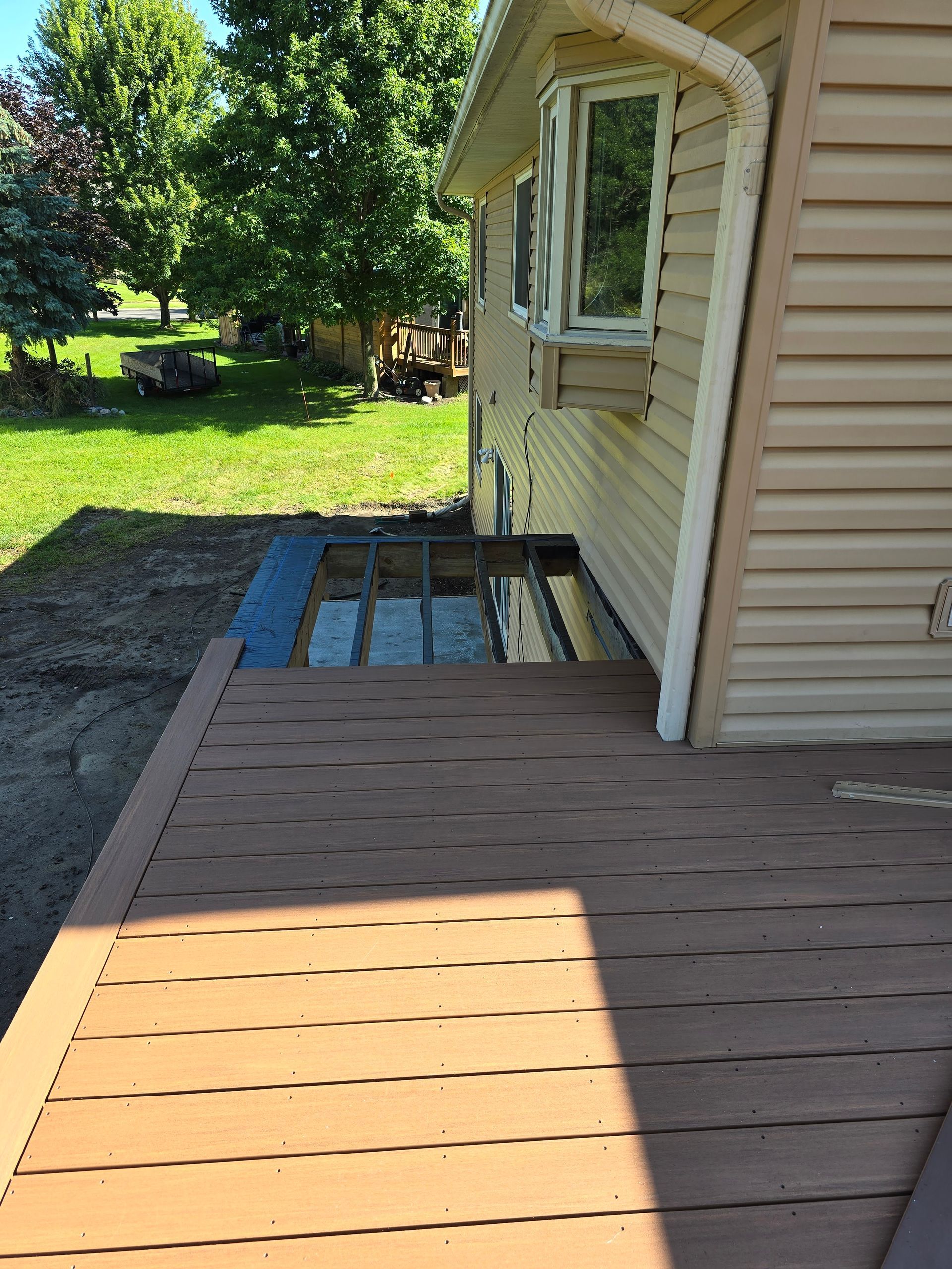 A wooden deck is sitting in front of a house.
