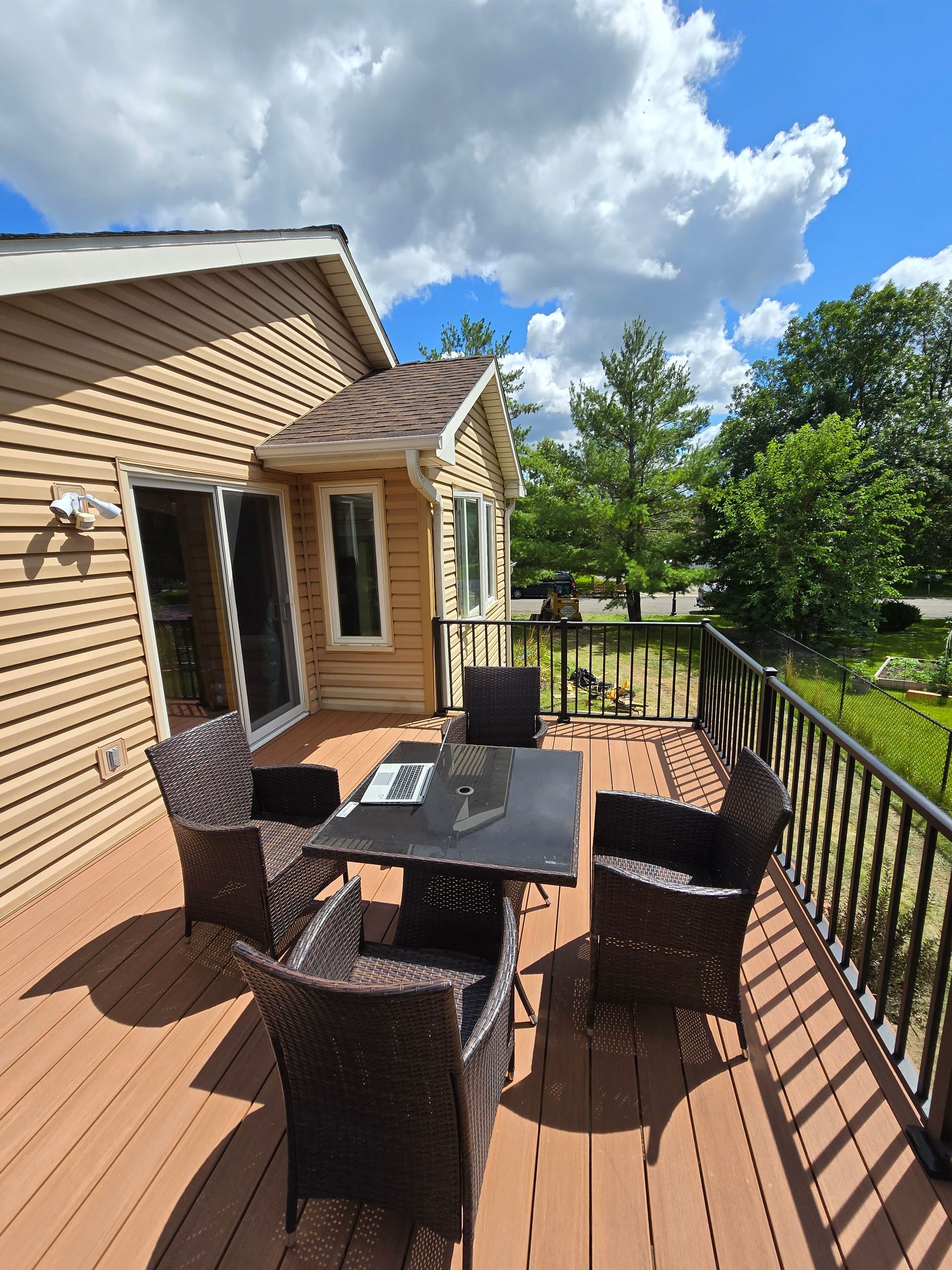 There is a table and chairs on the deck of a house.