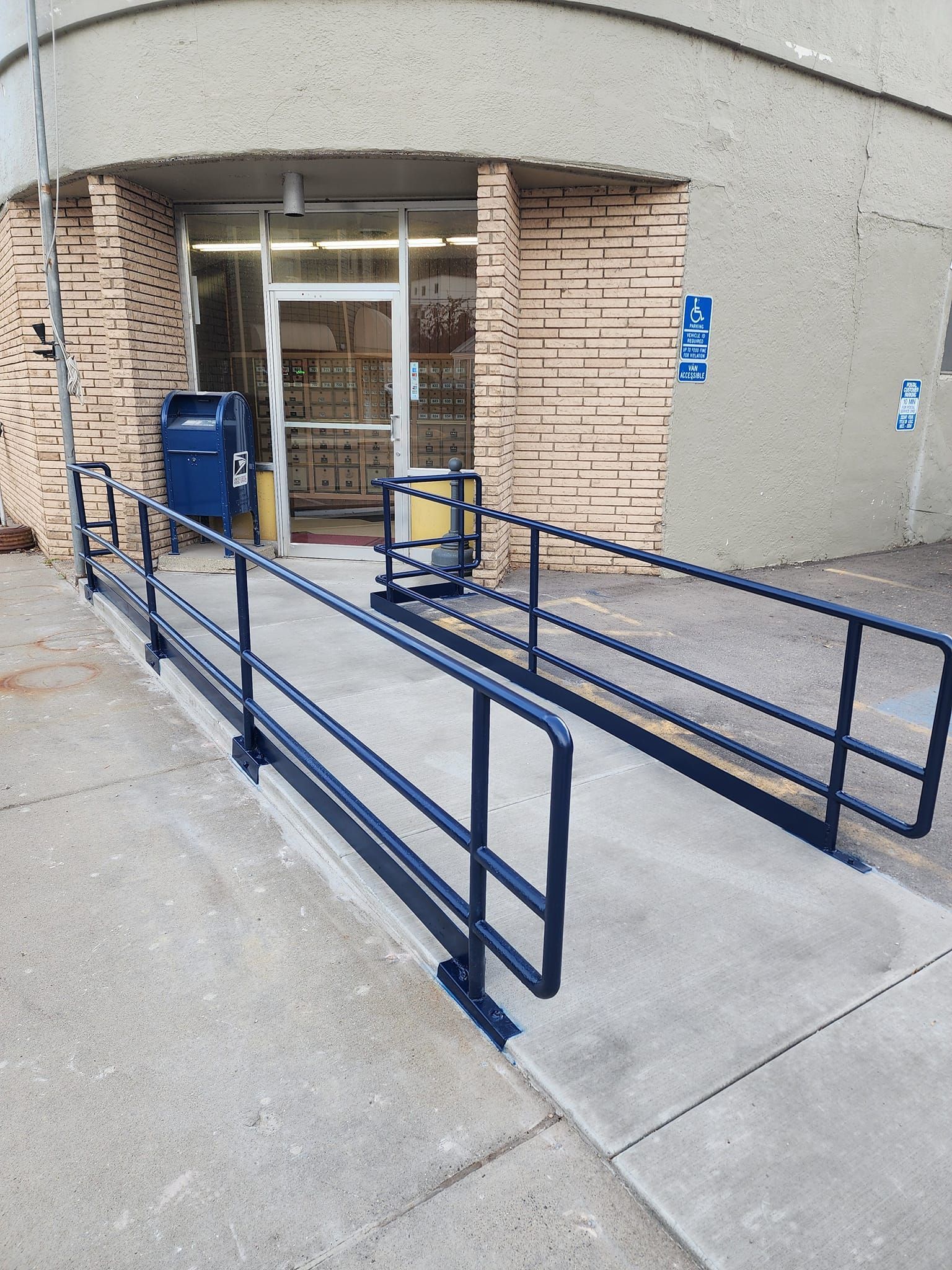 A ramp with a blue railing leading to a building