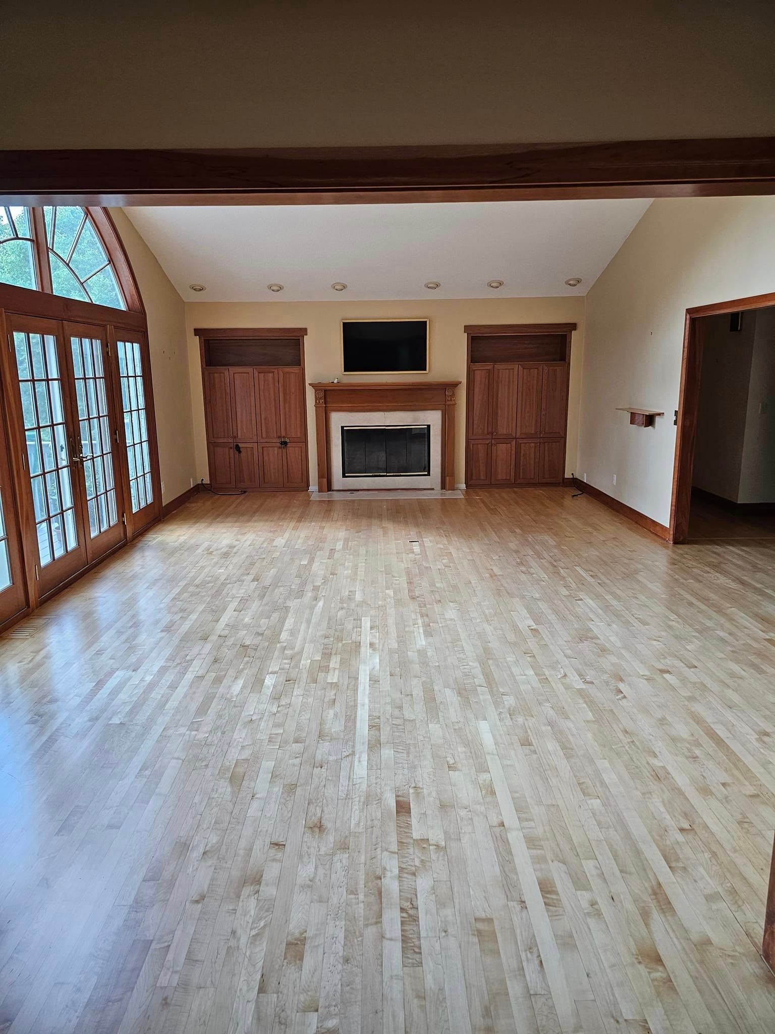 An empty living room with hardwood floors and a fireplace.