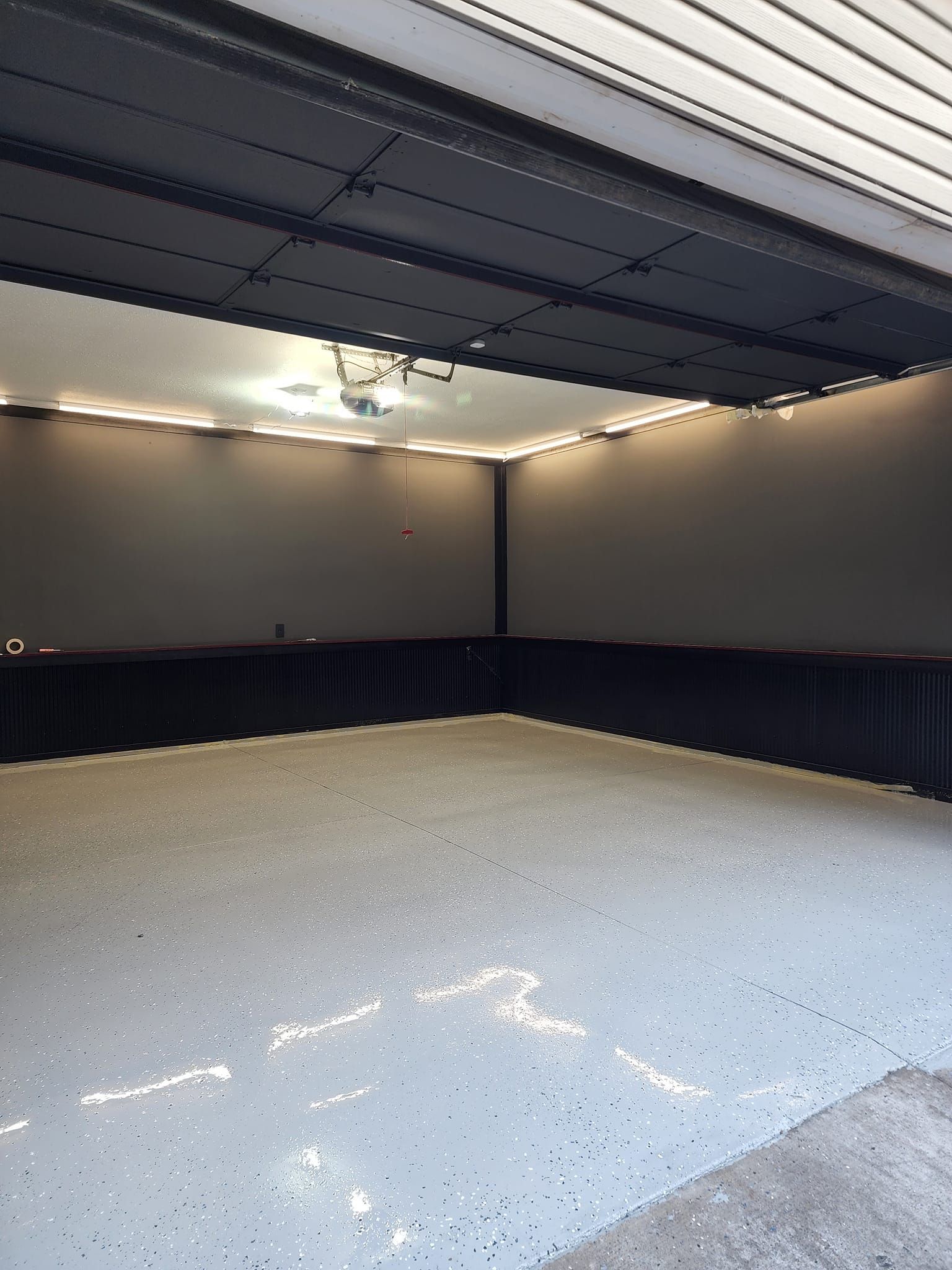 An empty garage with a white floor and black walls