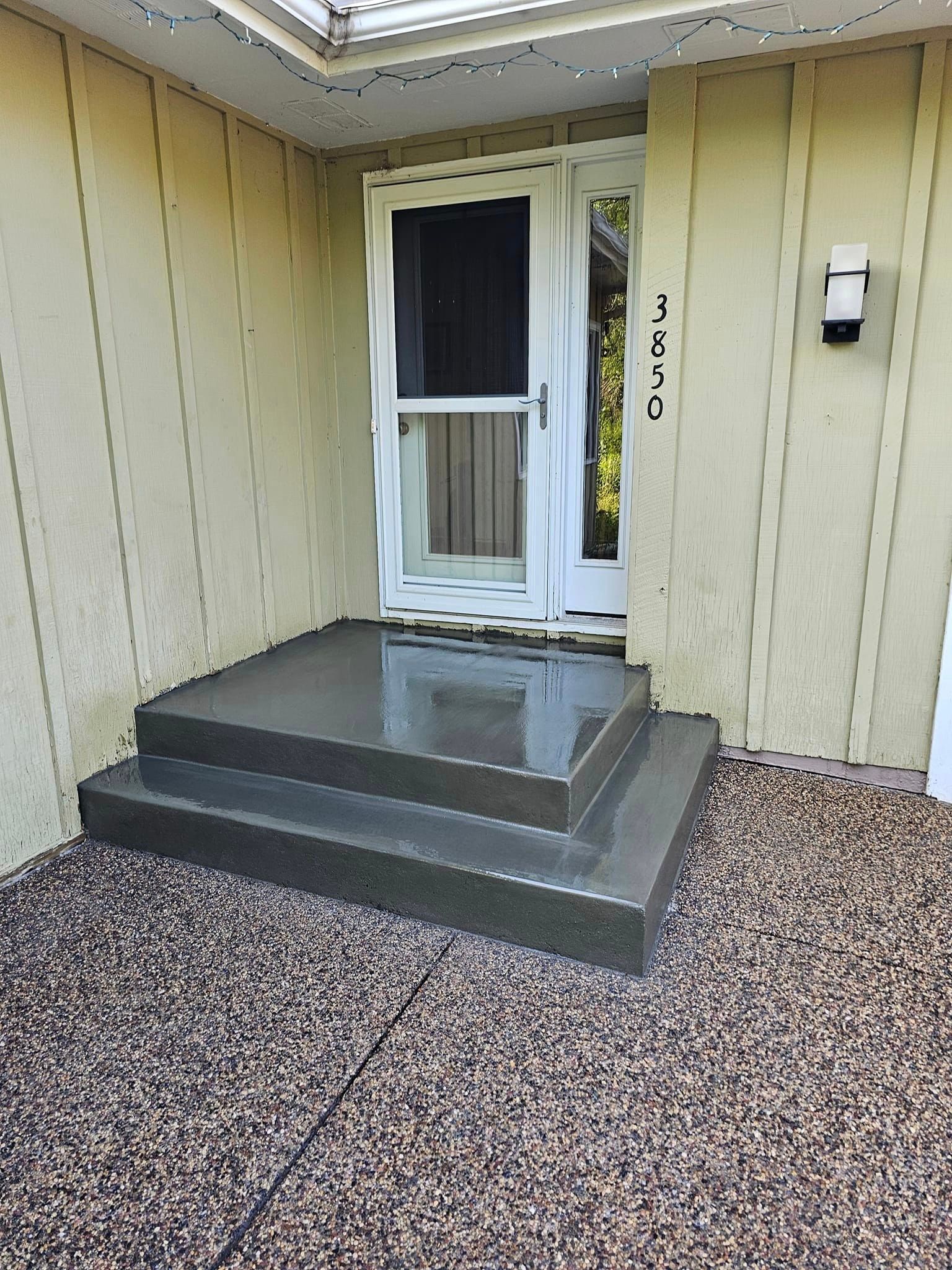 A front porch with concrete steps leading to a door.