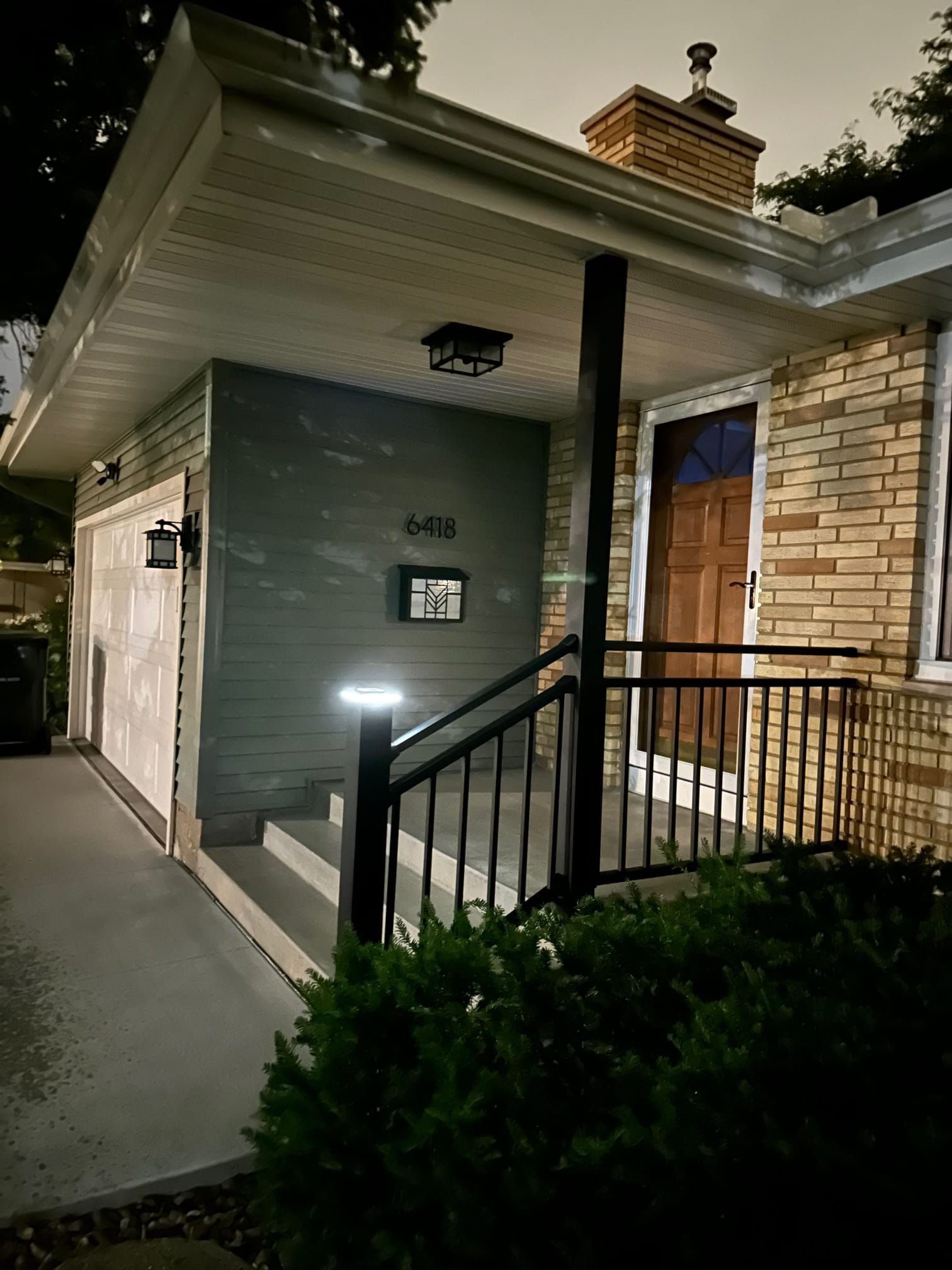 A brick house with a porch and stairs at night.