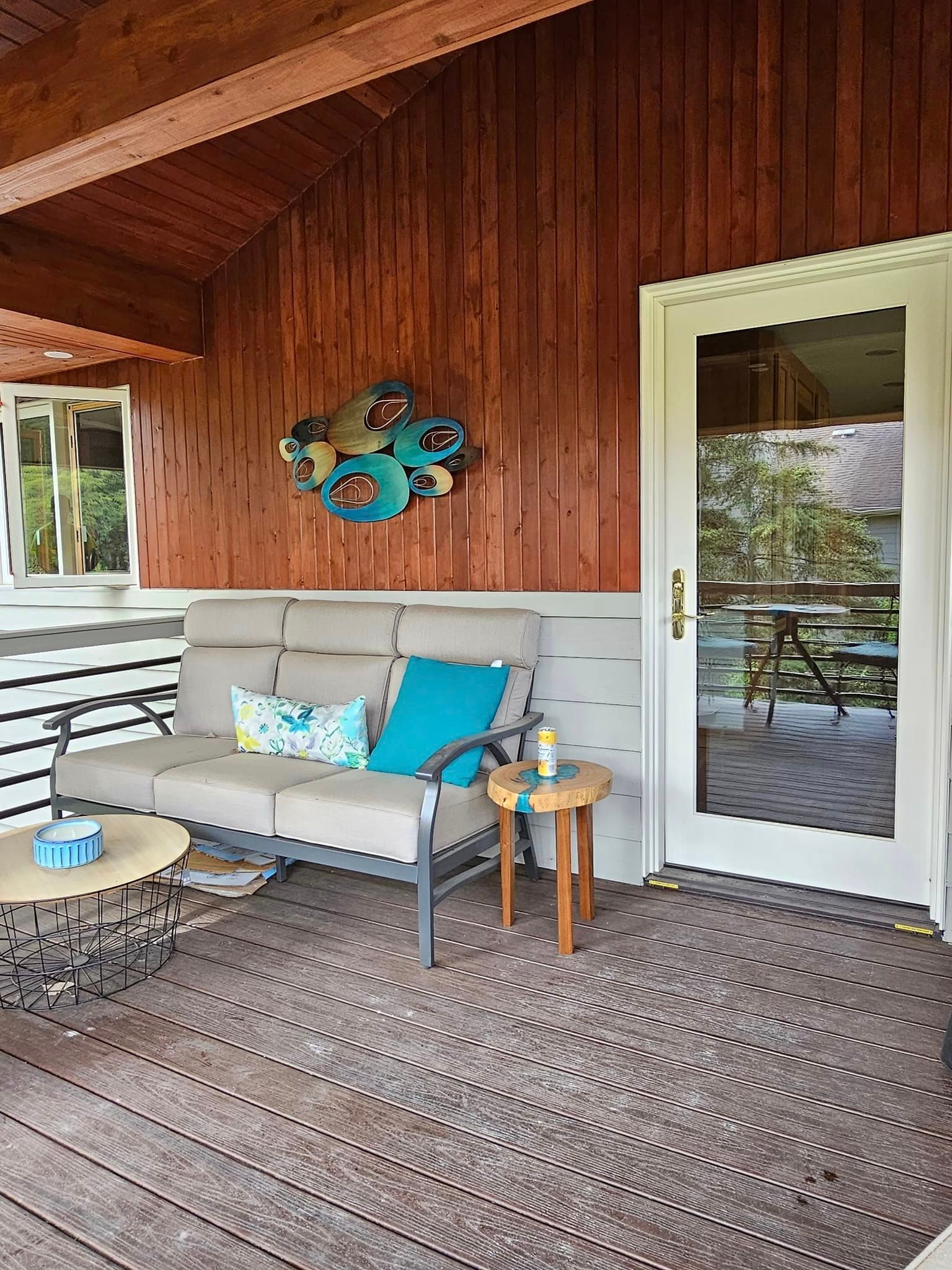 There is a couch and a table on the porch of a house.