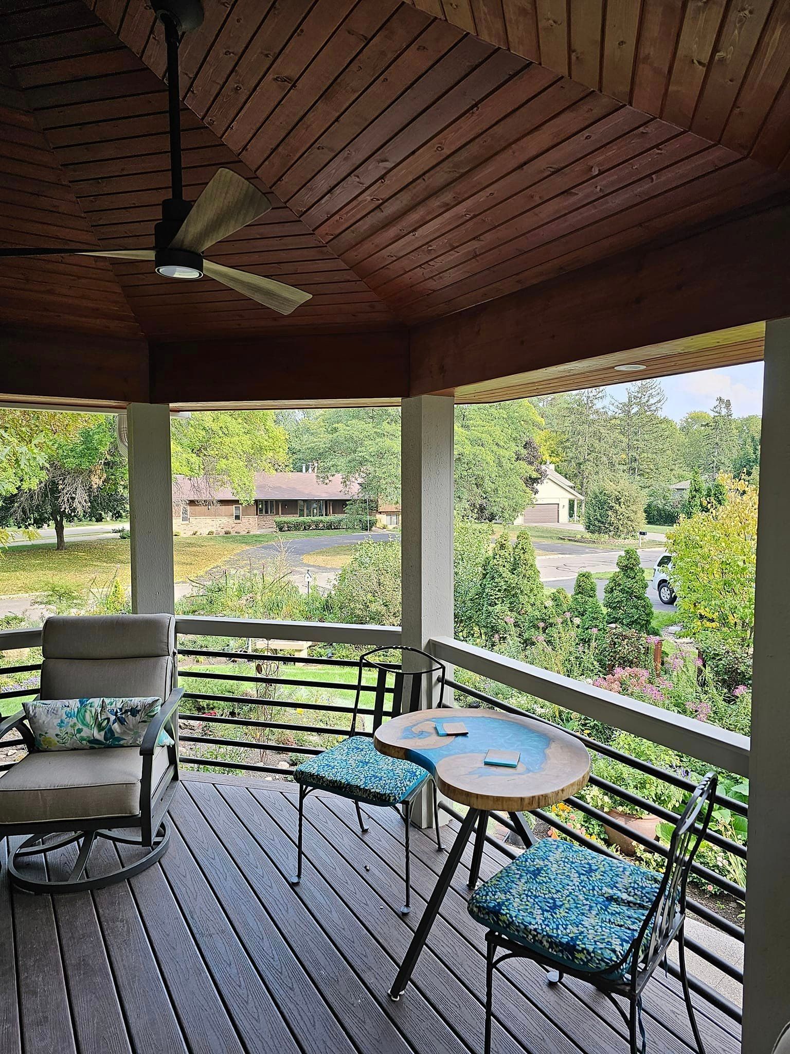 A porch with a table and chairs and a ceiling fan.